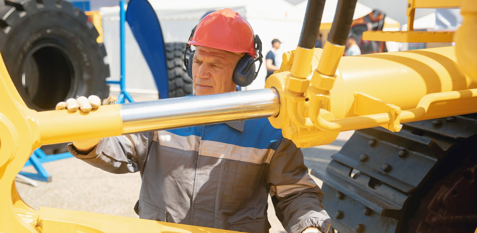 man with hardhat working with yellow machinery